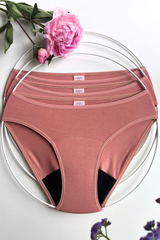 Tři kusy menstruačních SAYU kalhotek v barvě růžové latte, pohled zepředu, foceno s květinou na bílém pozadí