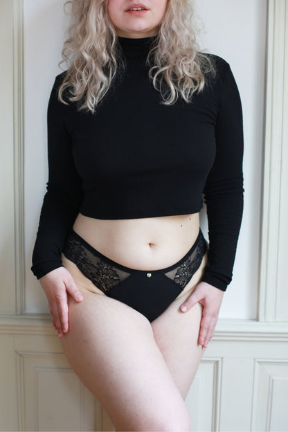 Menstruační kalhotky klasického střihu s krajkou v černé barvě a střední savosti na modelce.