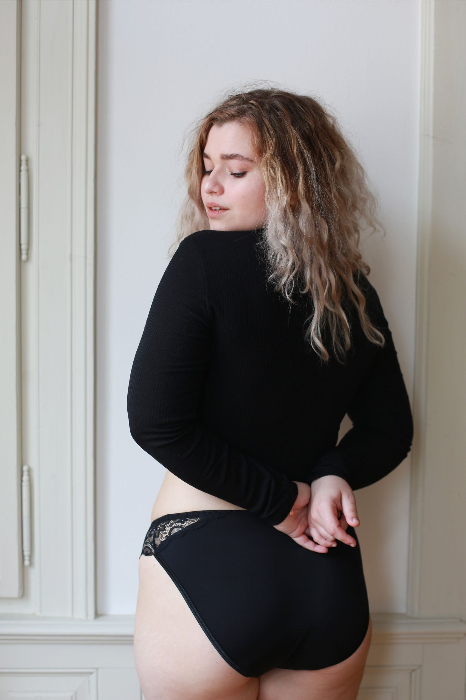 Pohled na zadní část černých menstruačních kalhotek s rafinovanou krajkou.