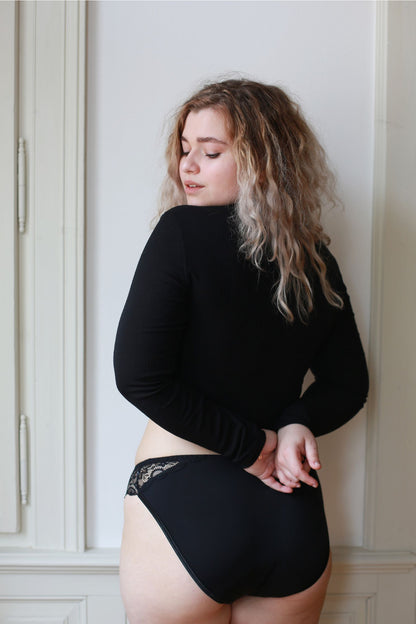 Pohled na zadní část černých menstruačních kalhotek s rafinovanou krajkou.