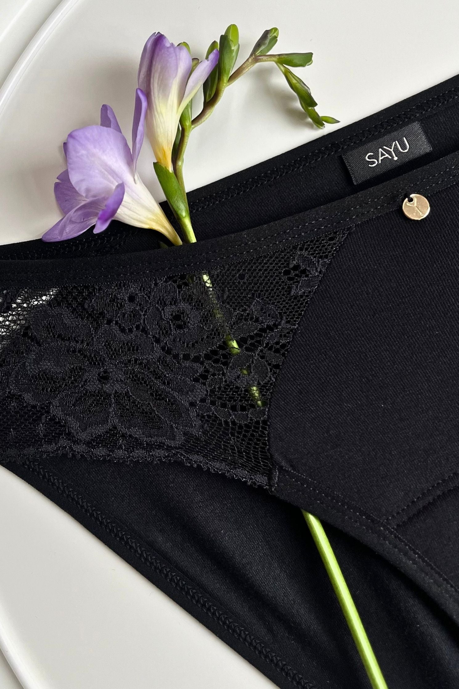 Detail na černou krajku a zdobný prvek černých menstruačních kalhotek SAYU.
