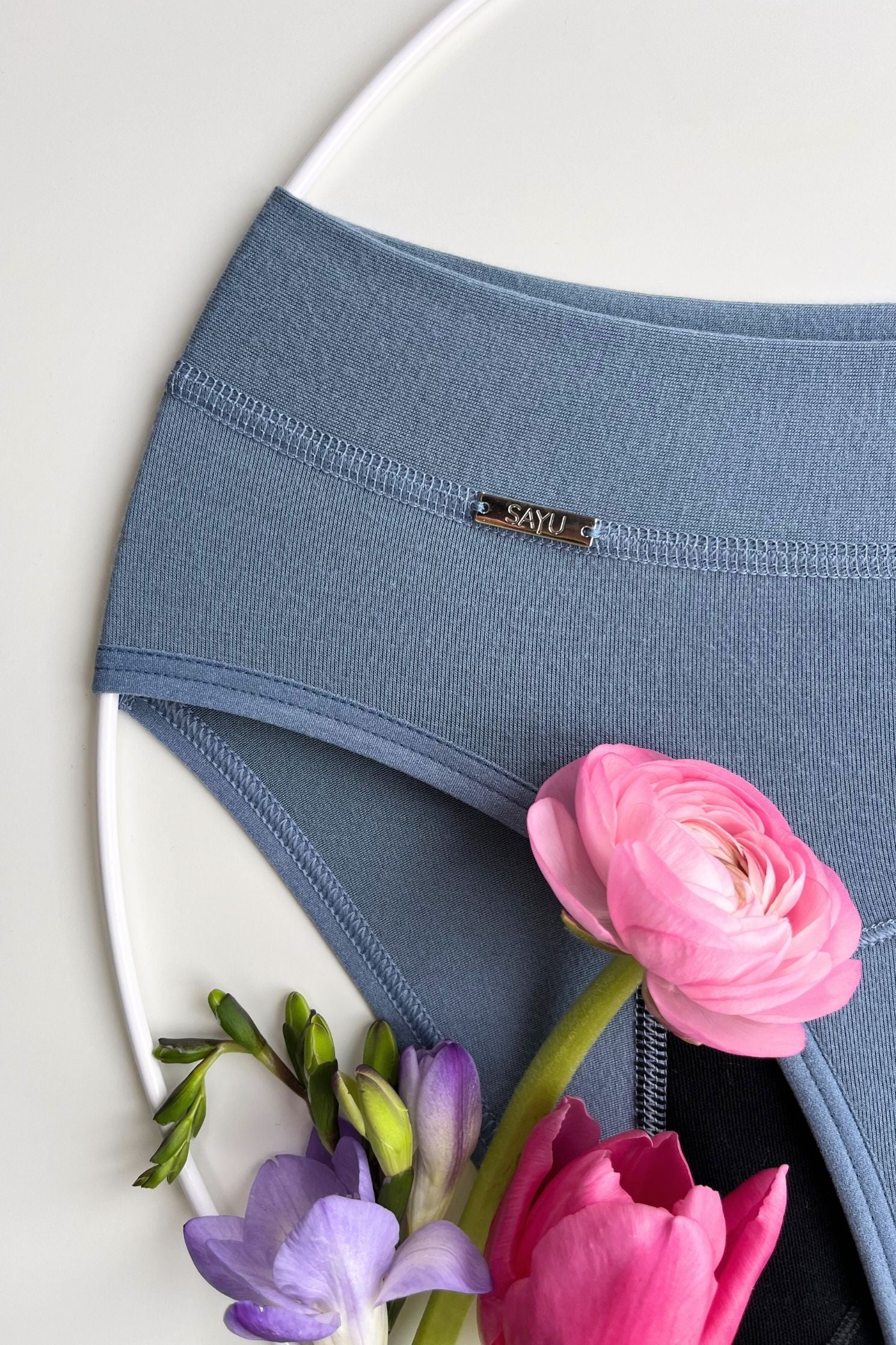 Noční menstruační kalhotky s prodlouženou merino vložkou ve střední savosti - detailní pohled na zdobný prvek a úplet kalhotek.