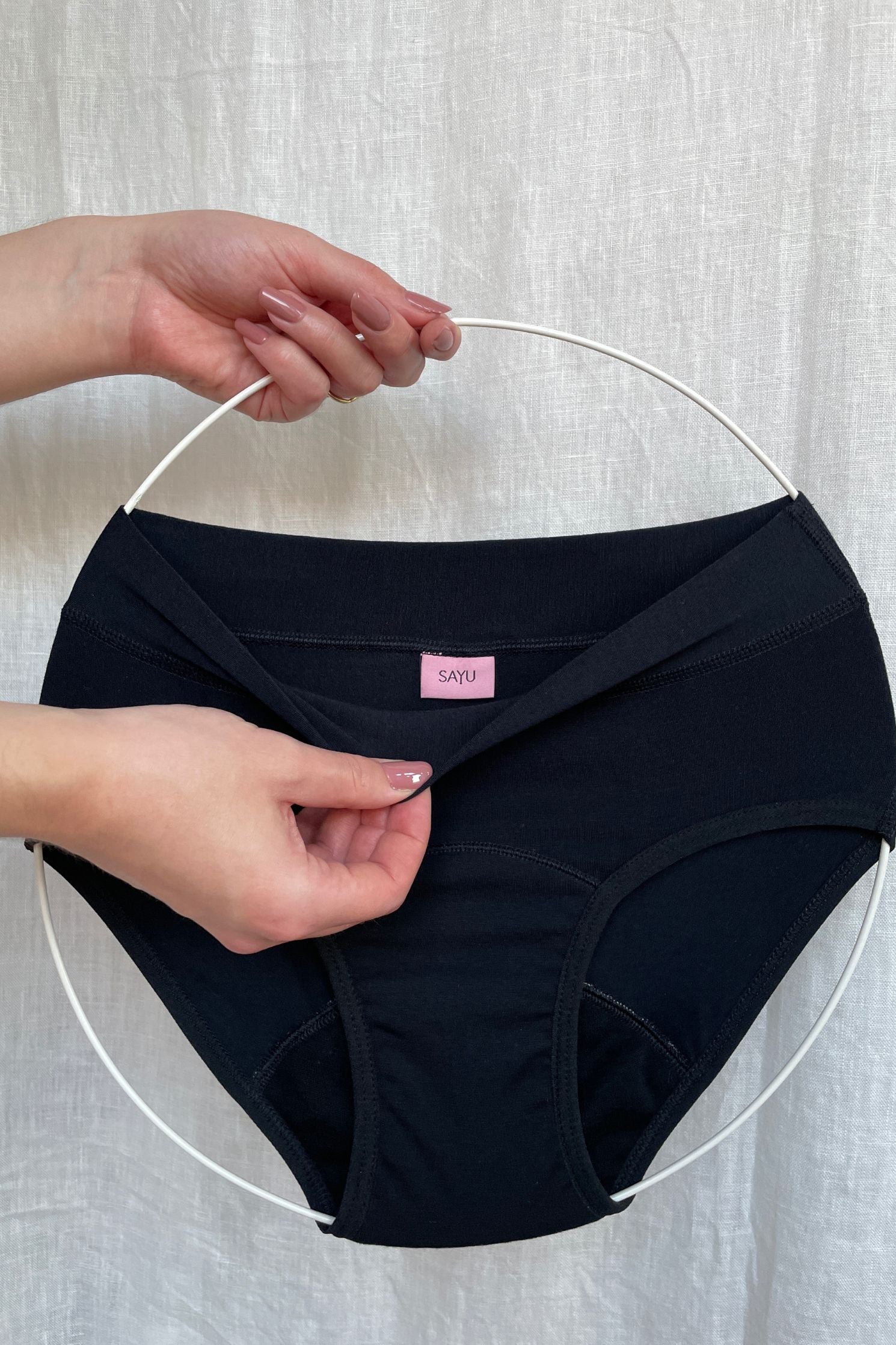 Produktová fotografie menstruačních kalhotek pro dívky. Přední pohled a detail etikety.